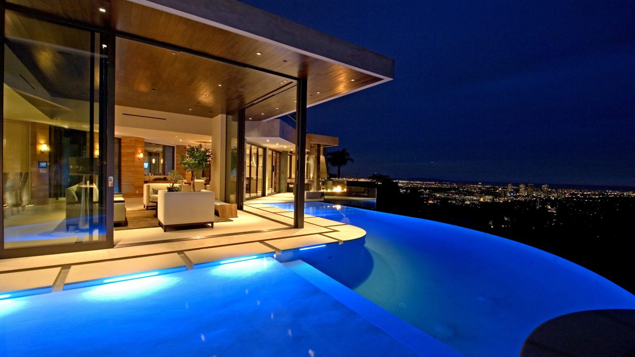Infinity pool outside patio of a beautiful home with an amazing view of the city at night | modern architecture firm in Los Angeles | Dean Larkin Design